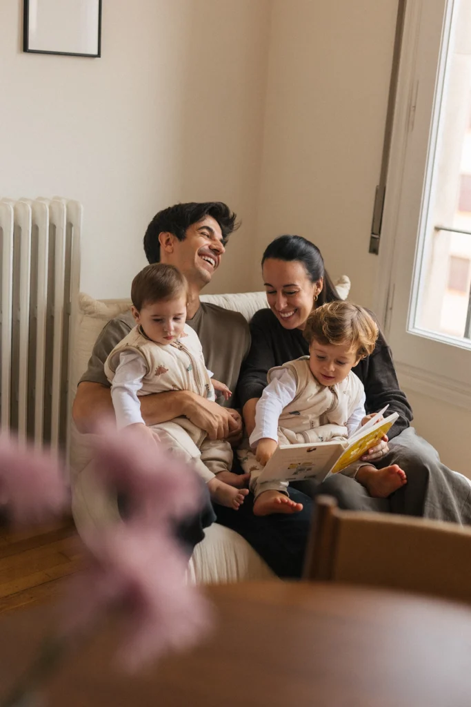 Familia con dos niños llevando pijamas de Molis&Co mientras leen un libro en casa