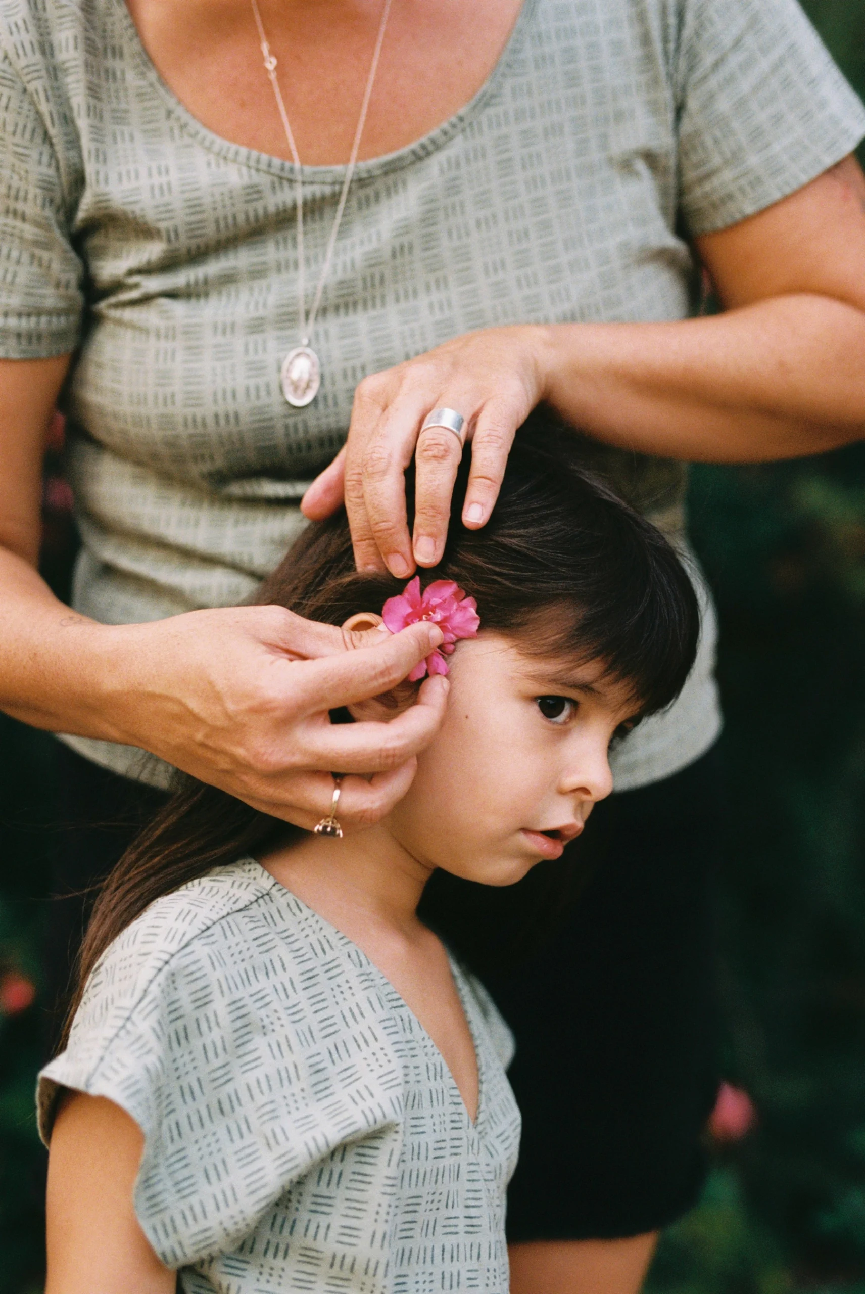 Madre poniendo una flor en el pelo de su hija durante una sesión de maternidad en exterior en Sabadell